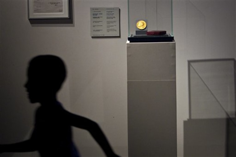 A boy runs past a Nobel Prize medal exhibited in the China Science and Technology Museum in Beijing.